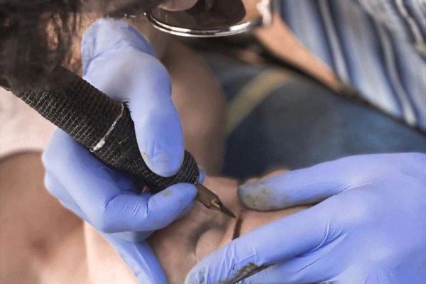 Мастер делает татуаж век клиенту