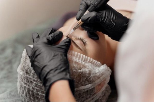 Мастер делает перманентный макияж бровей
