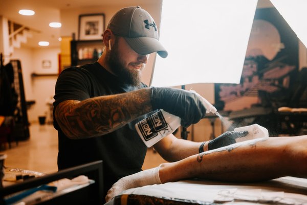 Майстер тату дезінфікує ногу клієнта