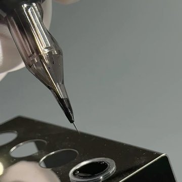 Тату-голка над капсулою чорного чорнила